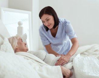 caregiver putting blanket to senior
