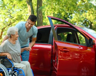 caregiver assisting senior transfer to vehicle
