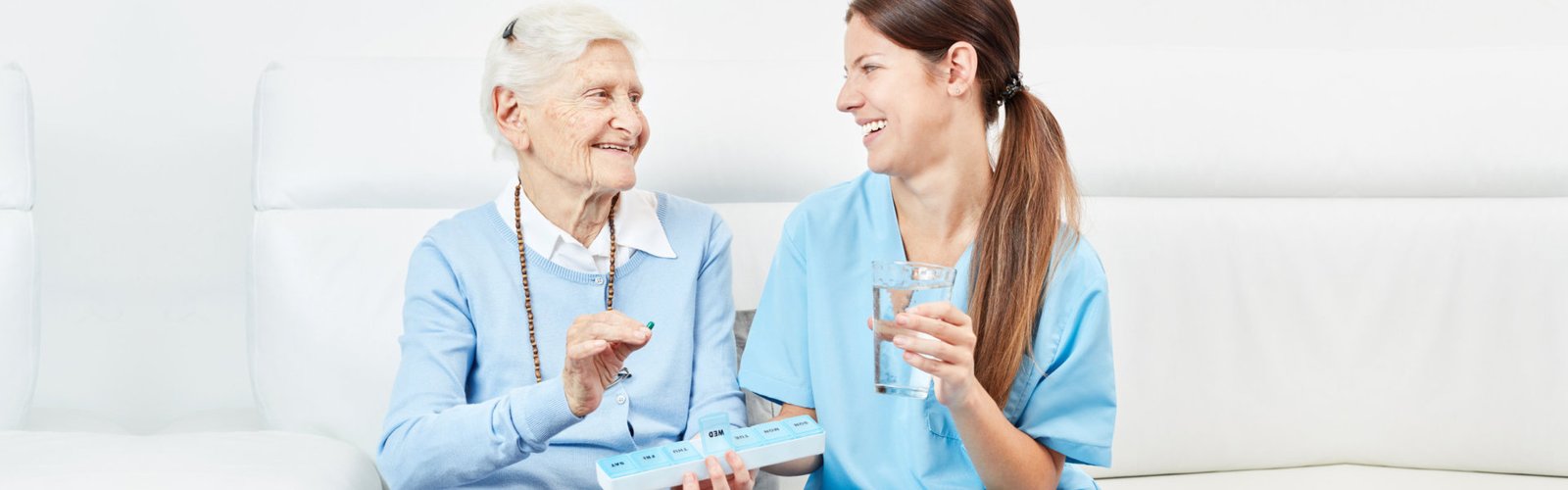 caregiver giving medicine to senior
